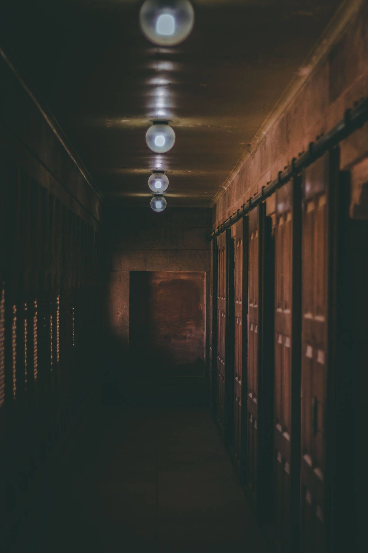 An Eerily Empty Hallway Illuminated With Dim Light Background