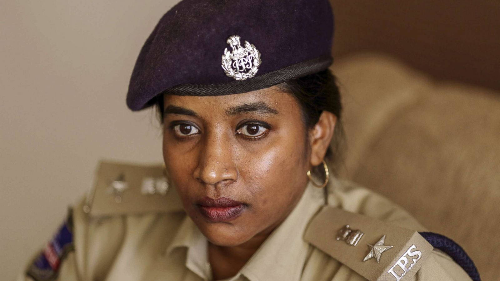 An Image Of A Female Officer Wearing A Cap With An Ips Logo. Background