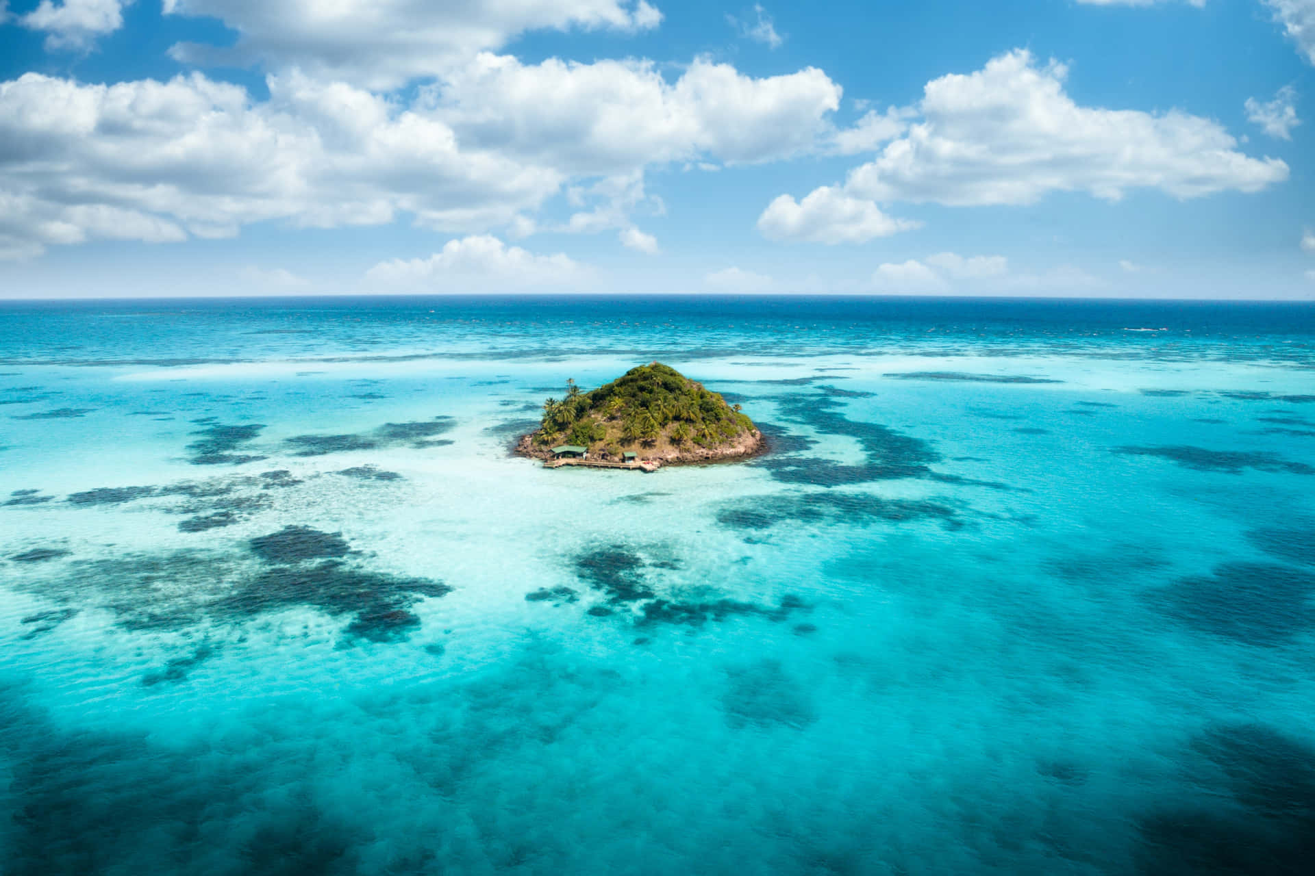 An Island In The Ocean With Blue Water And Clouds Background