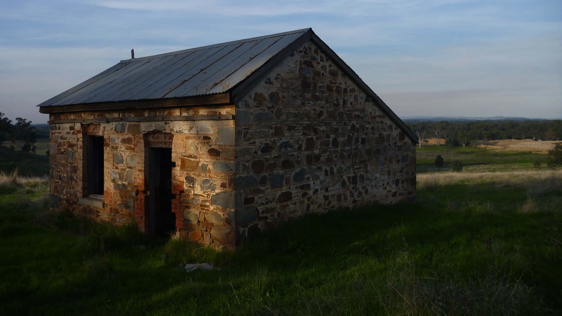 An Old Stone Building In A Field Background