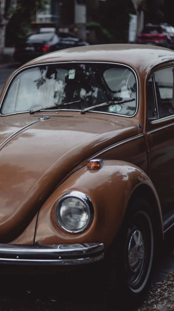 An Old Tan Volkswagen Beetle Parked On The Side Of The Road