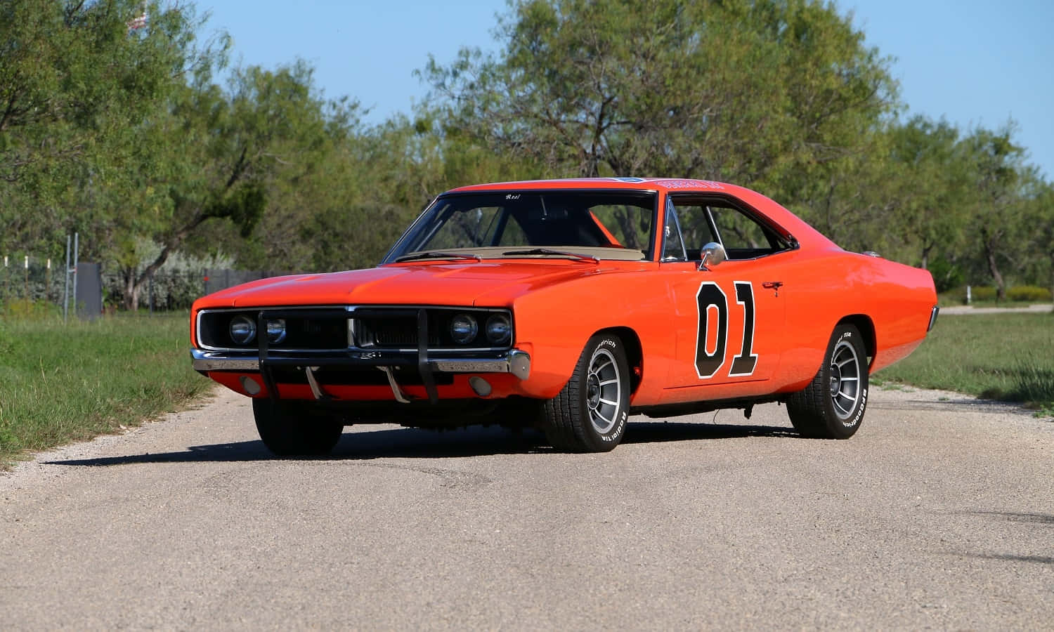 An Orange Car Is Driving Down A Road Background