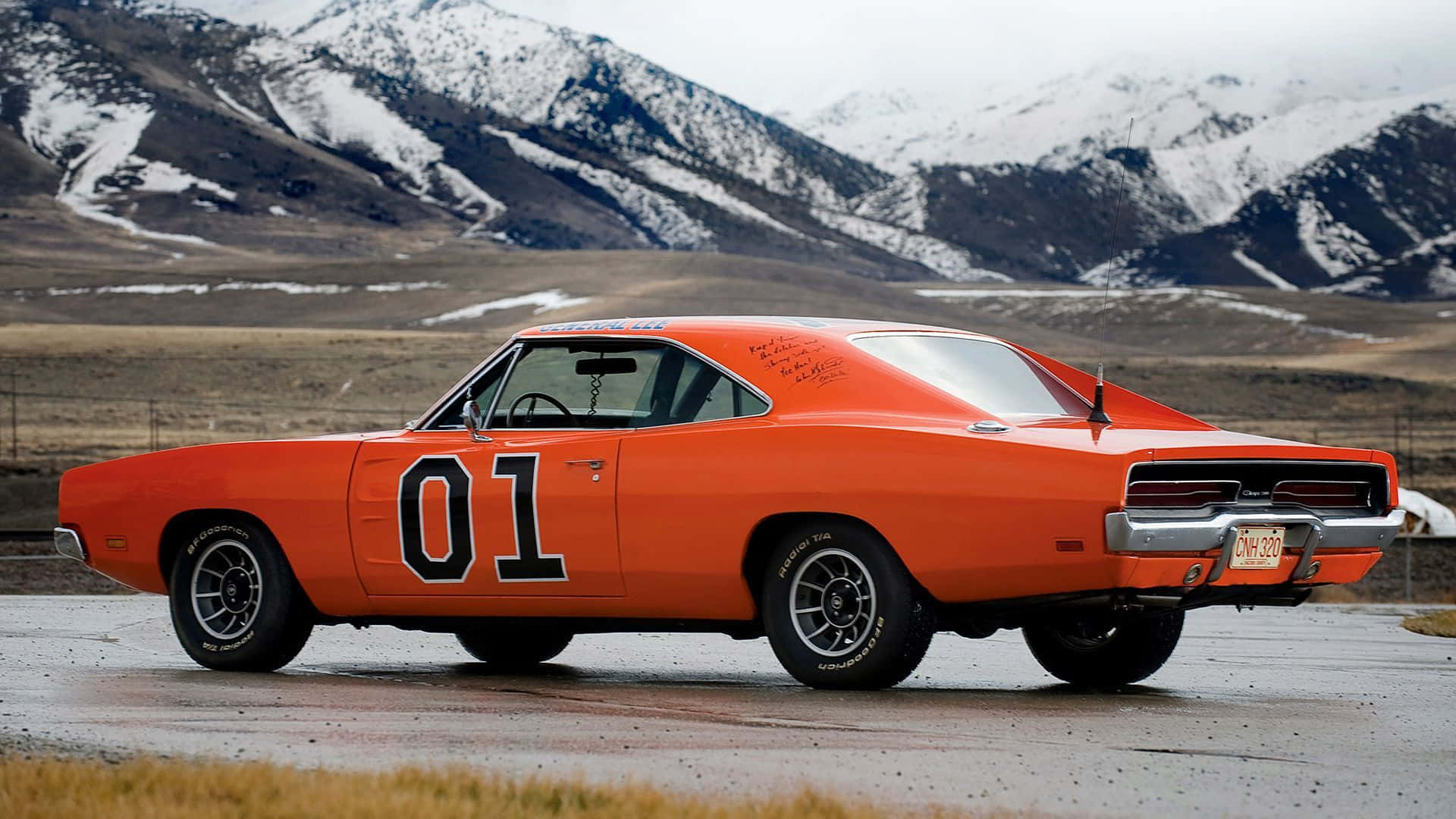 An Orange Dodge Charger Is Driving Down The Road Background