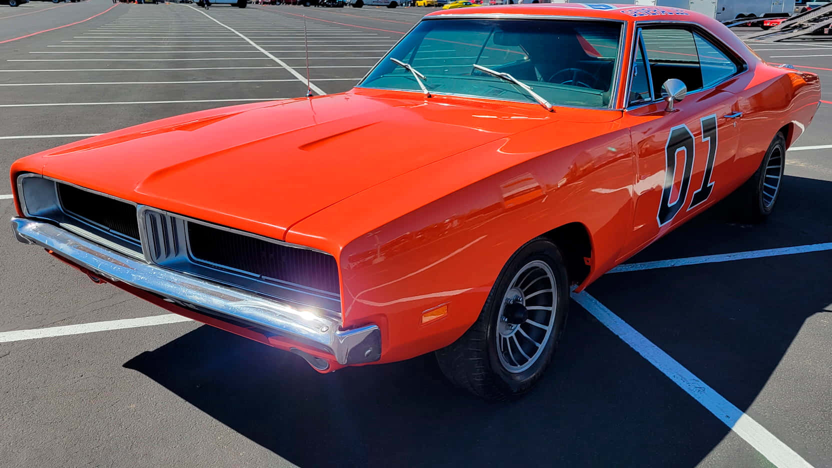 An Orange Dodge Charger Parked In A Parking Lot Background