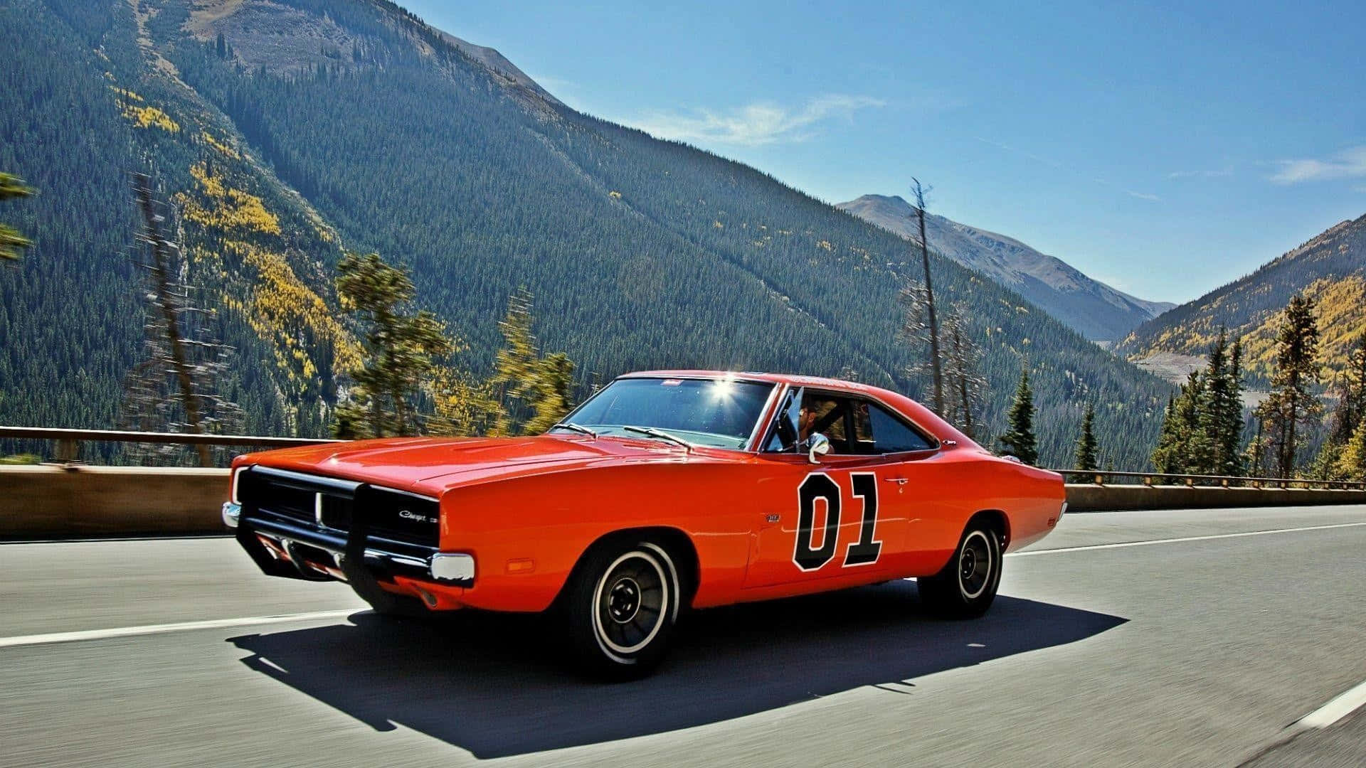 An Orange Muscle Car Driving Down A Mountain Road Background