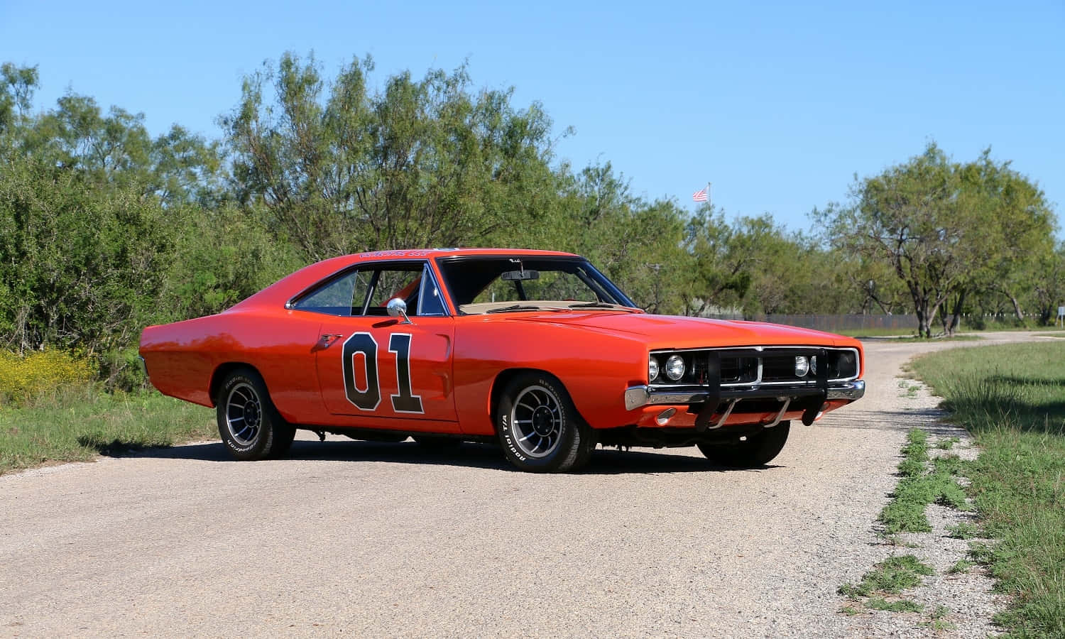 An Orange Muscle Car Is Driving Down A Dirt Road Background