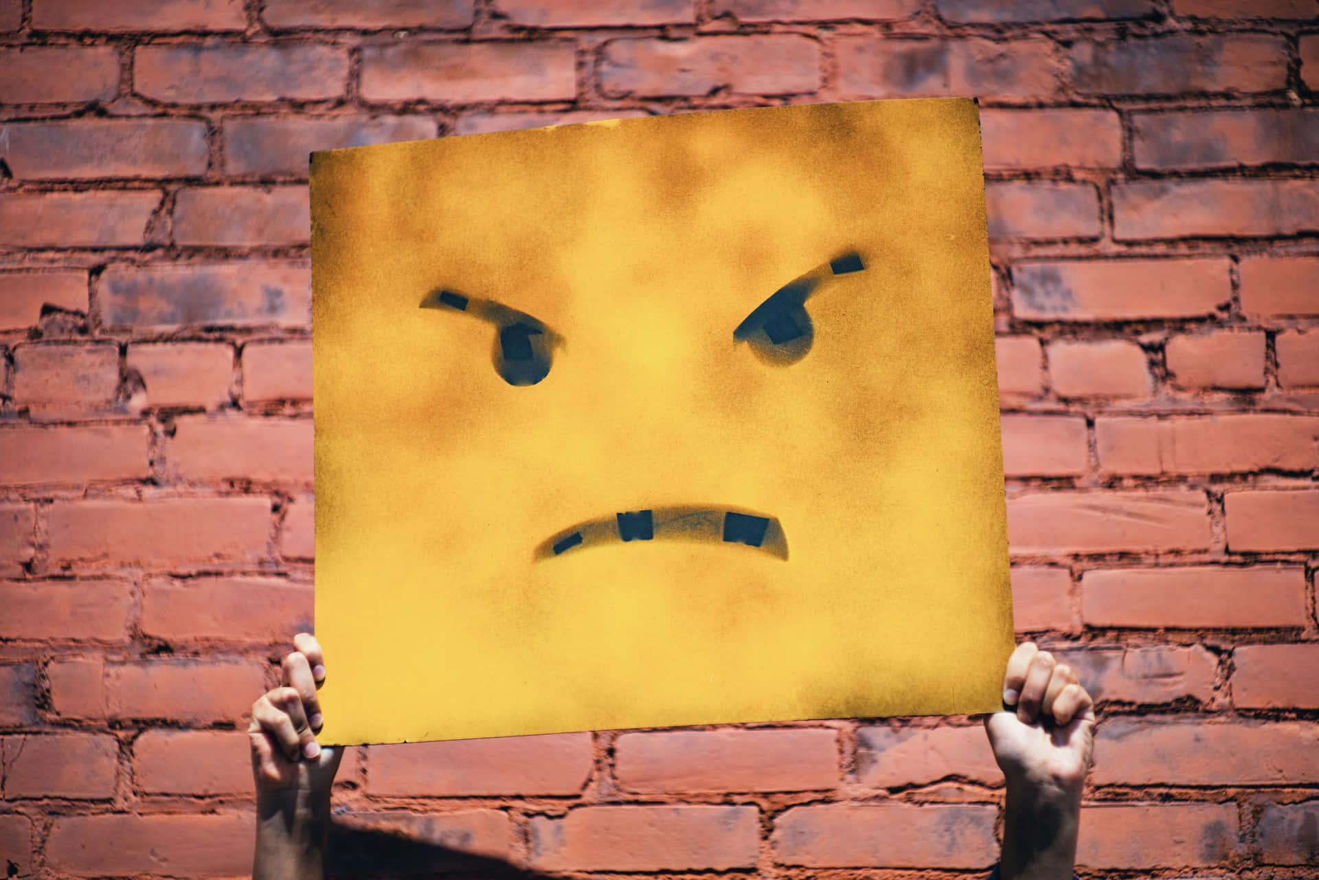 Angry Face Placard Against Brick Wall Background