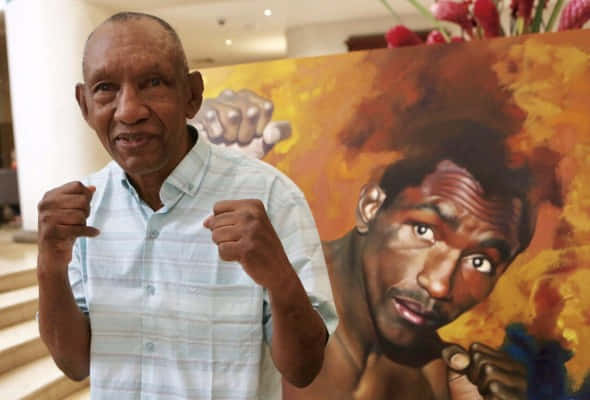 Antonio Cervantes And A Painting Of Younger Him Background