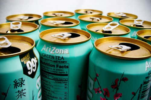 Arizona Tea Cans With Gold And Pink Flowers Background