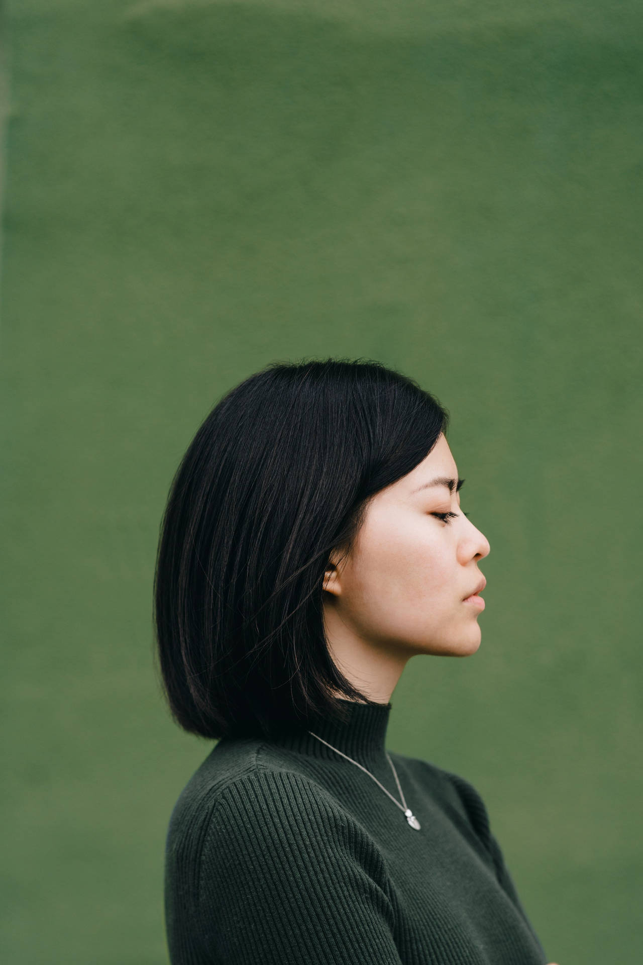 Asian Woman In Dark Green Turtleneck Background
