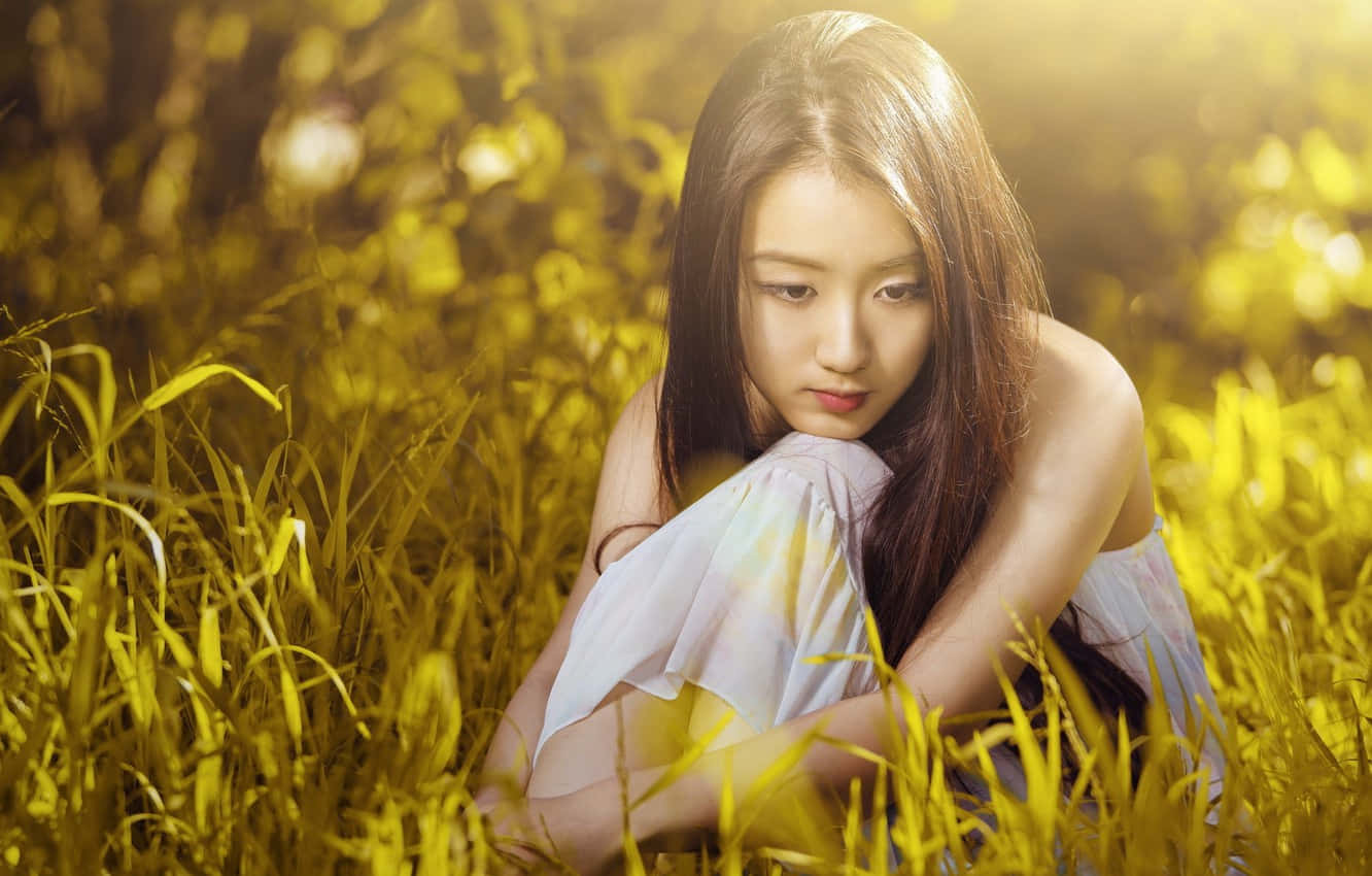 Asian Woman Sitting On Grass Background