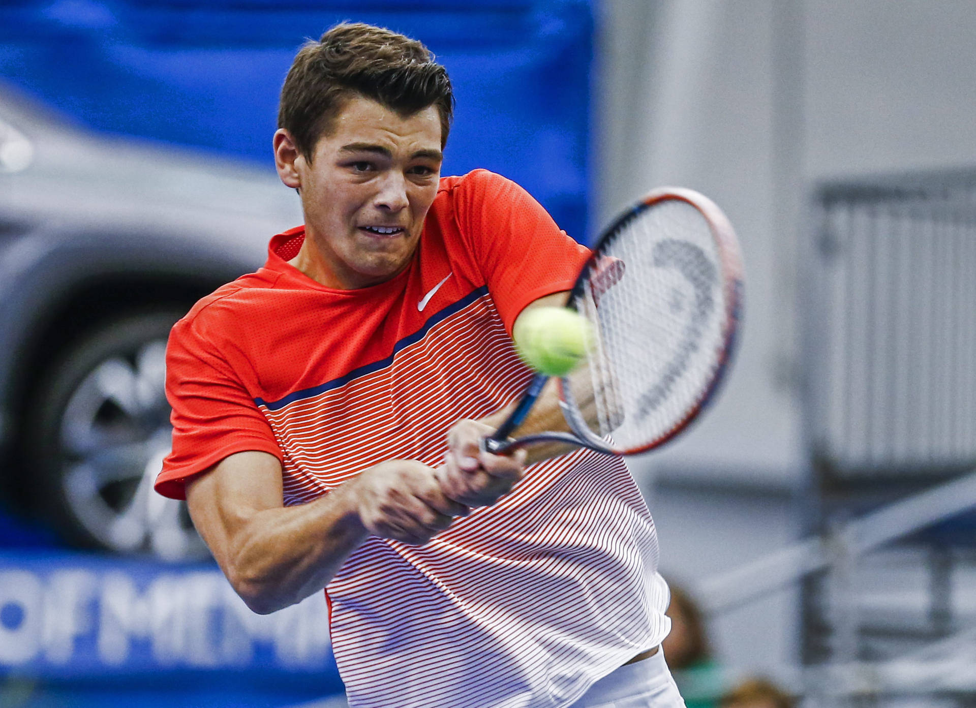 Athlete Taylor Fritz Hitting The Ball Background