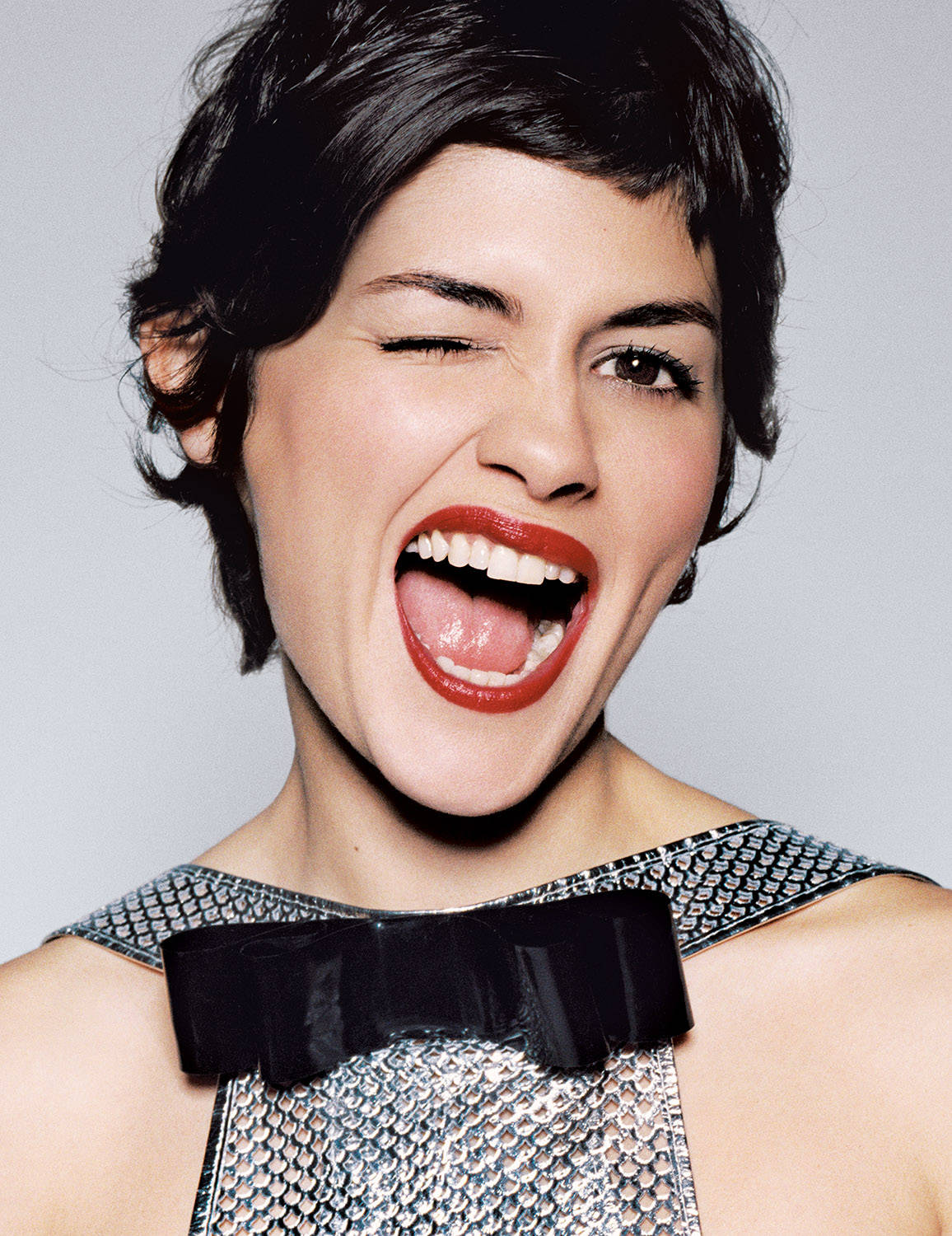 Audrey Tautou Winking In Elegant Silver Dress Background