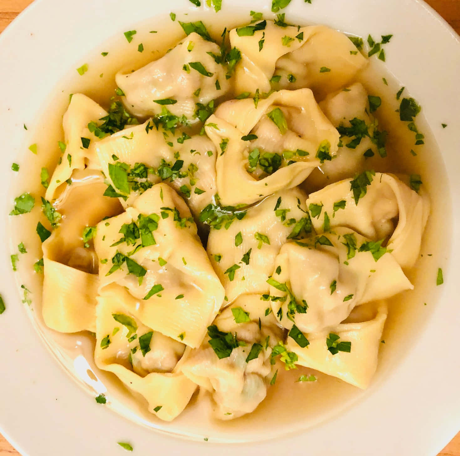 Authentic Tortellini In Brodo Garnished With Fresh Greens Background