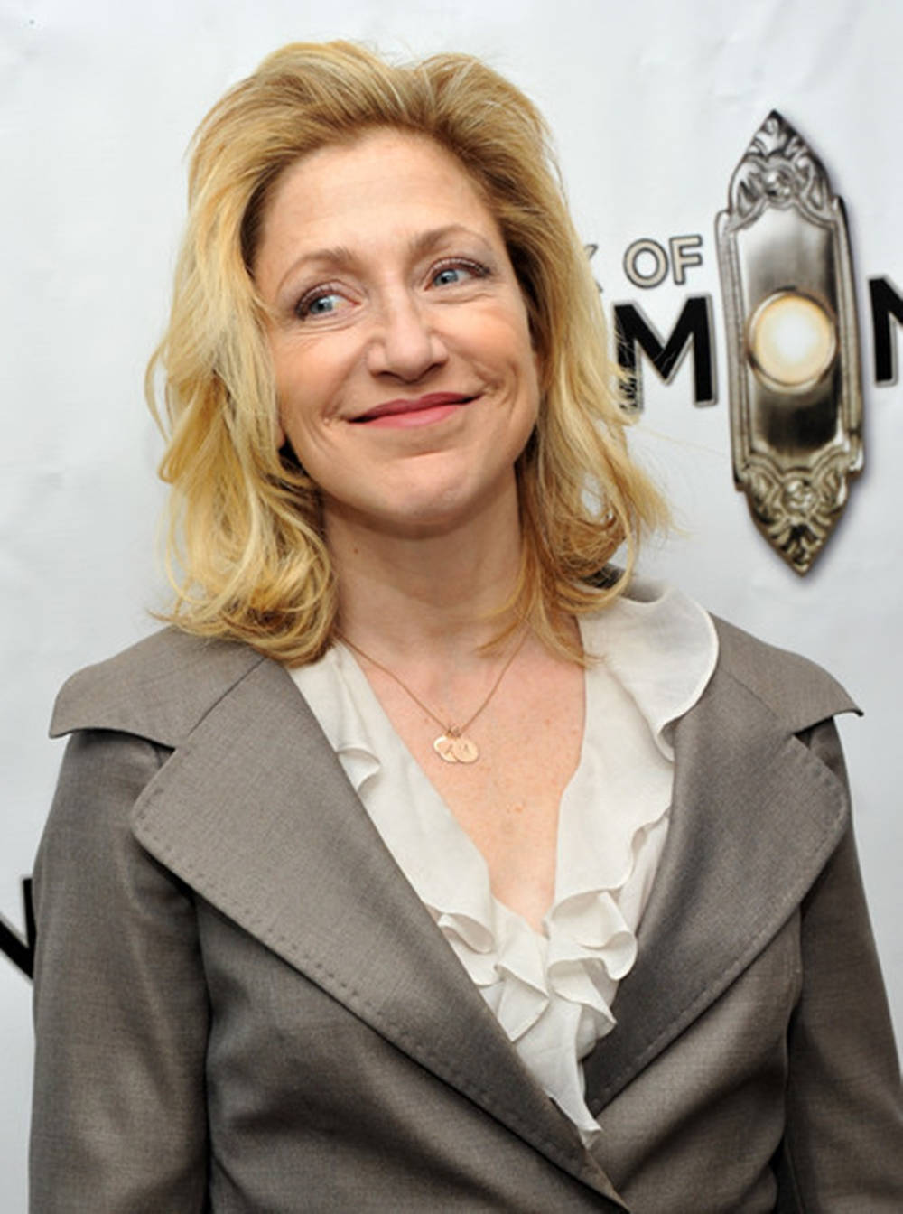 Award-winning Actress Edie Falco In Grey Suit Over White Ruffle Top Background