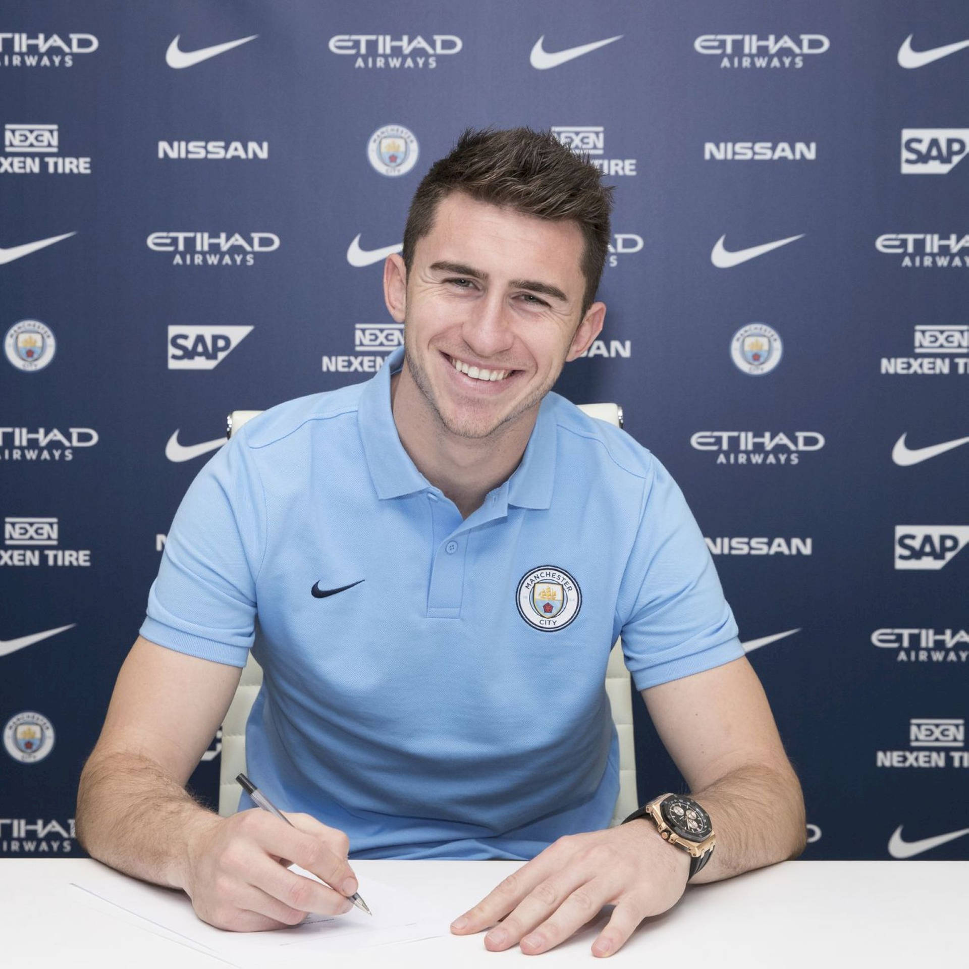 Aymeric Laporte Smiling And Holding Pen Background