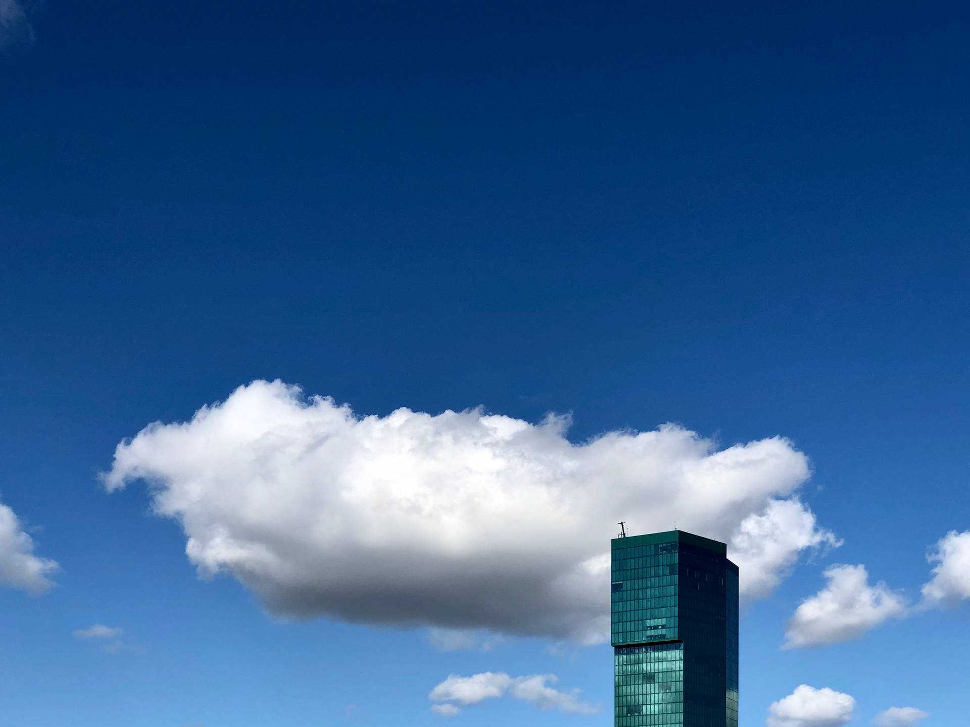 Azure Cloudy Sky With Green Building Background