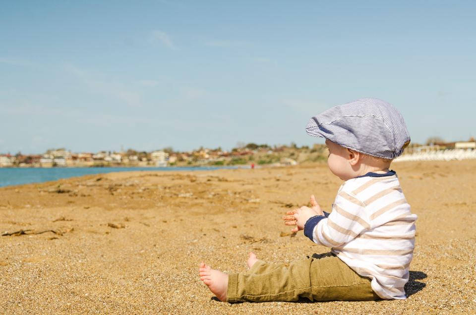 Baby Boy Seated On The Beach Background