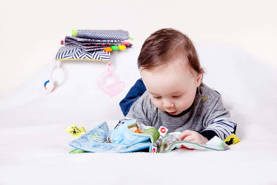 Baby Engaged With Educational Book Background