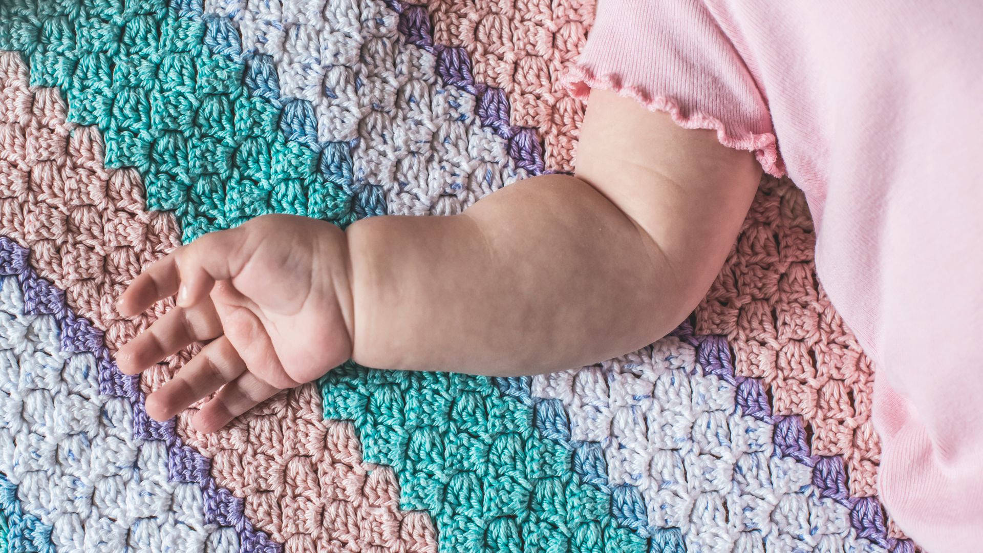 Baby Hand On A Colorful Fabric Background