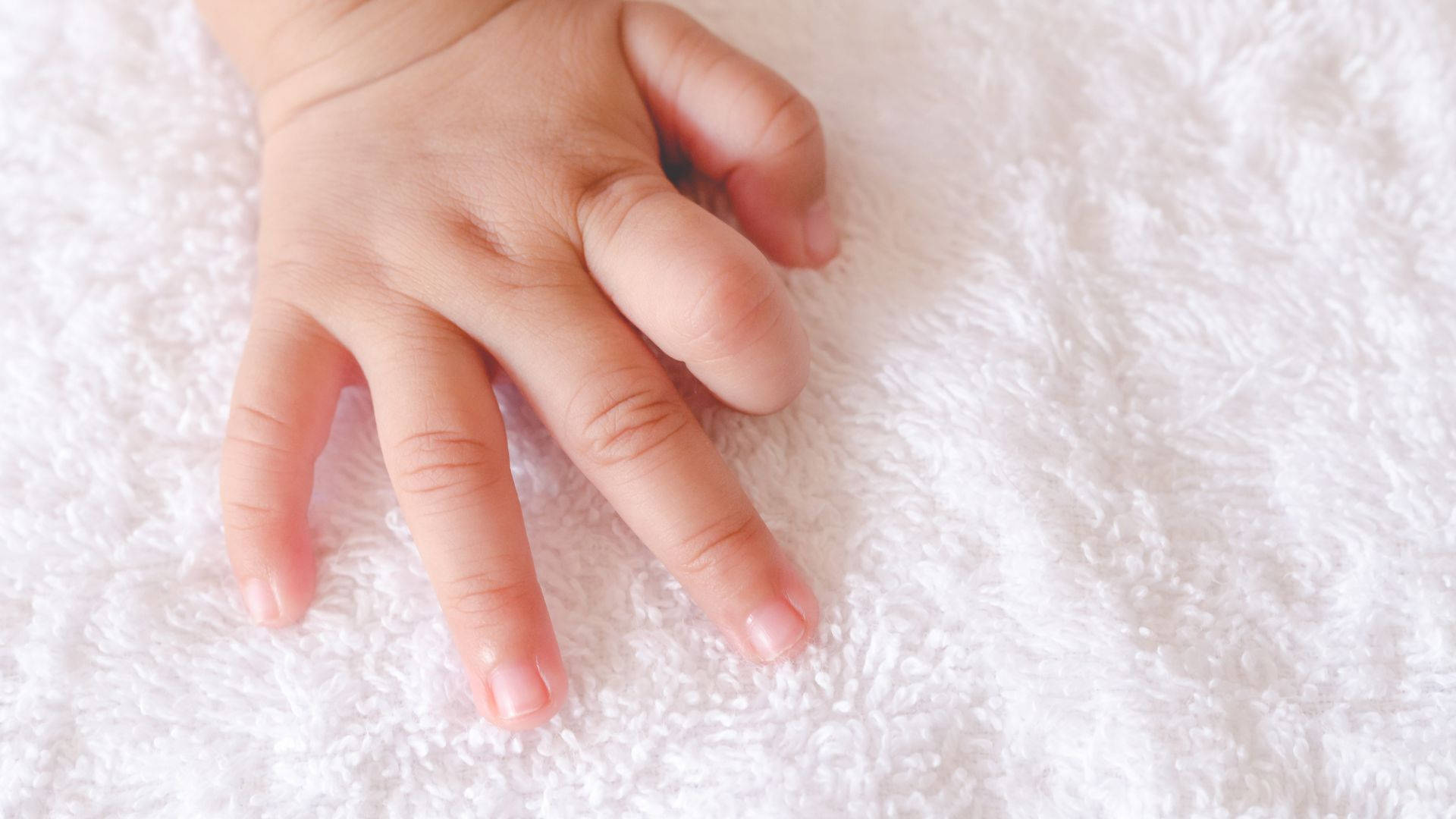 Baby Hand Touching A Soft Fabric Background