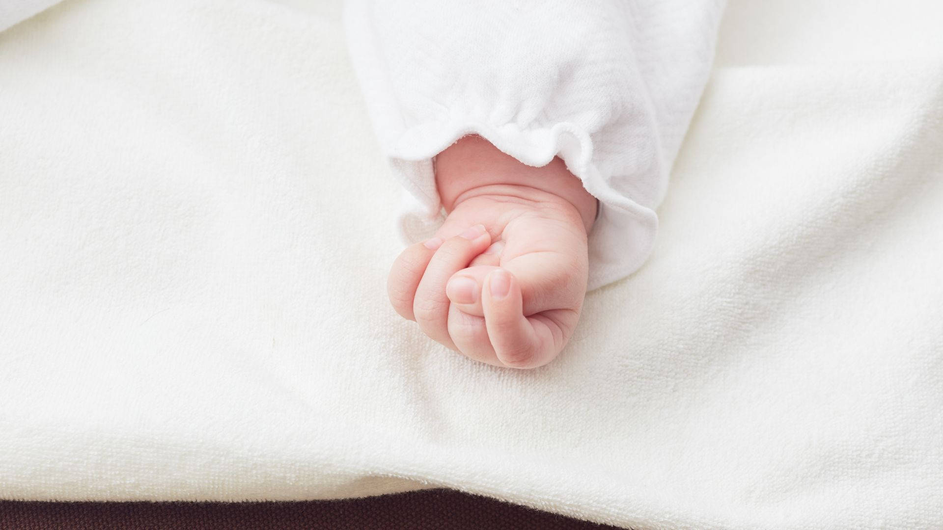 Baby Hand Wearing A White Outfit Background