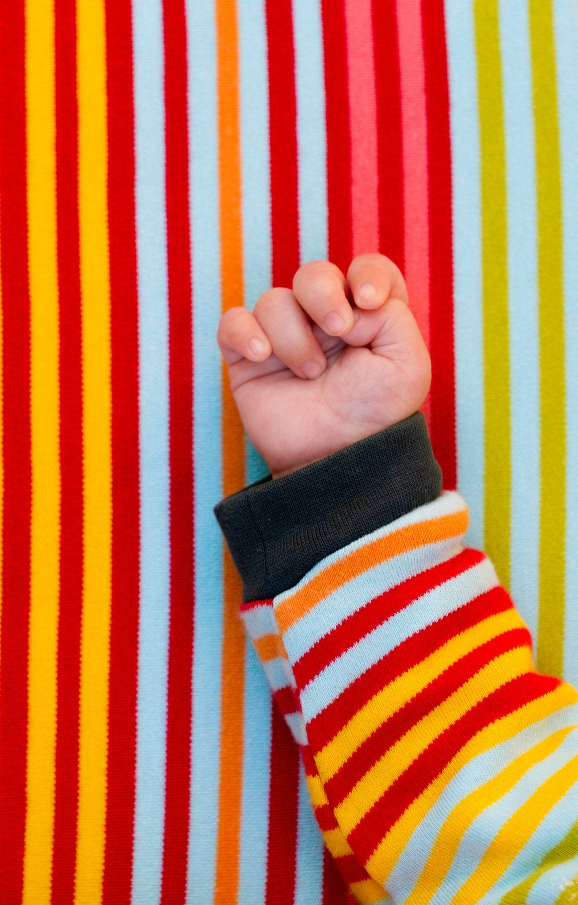 Baby Hand Wearing Colorful Sweater Background