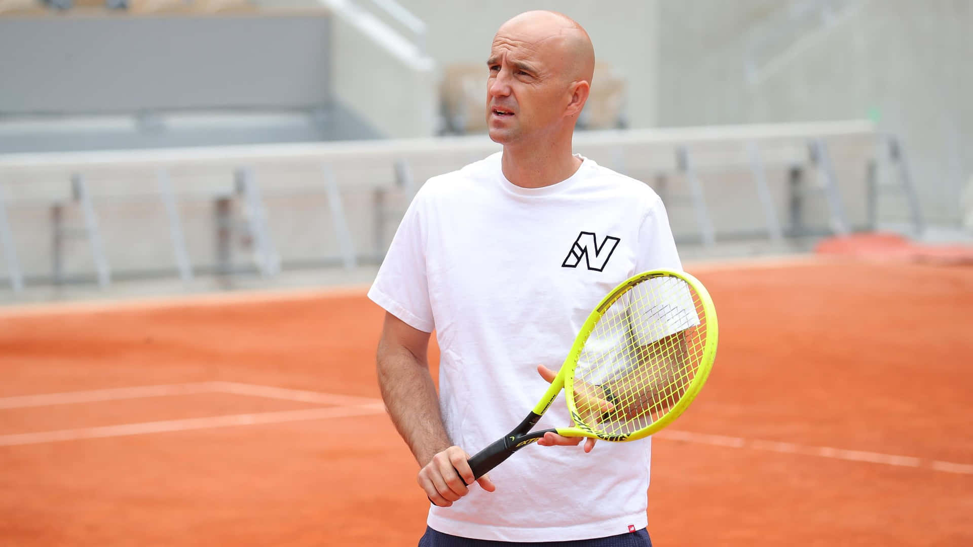 Bald Tennis Coach On Clay Court Background