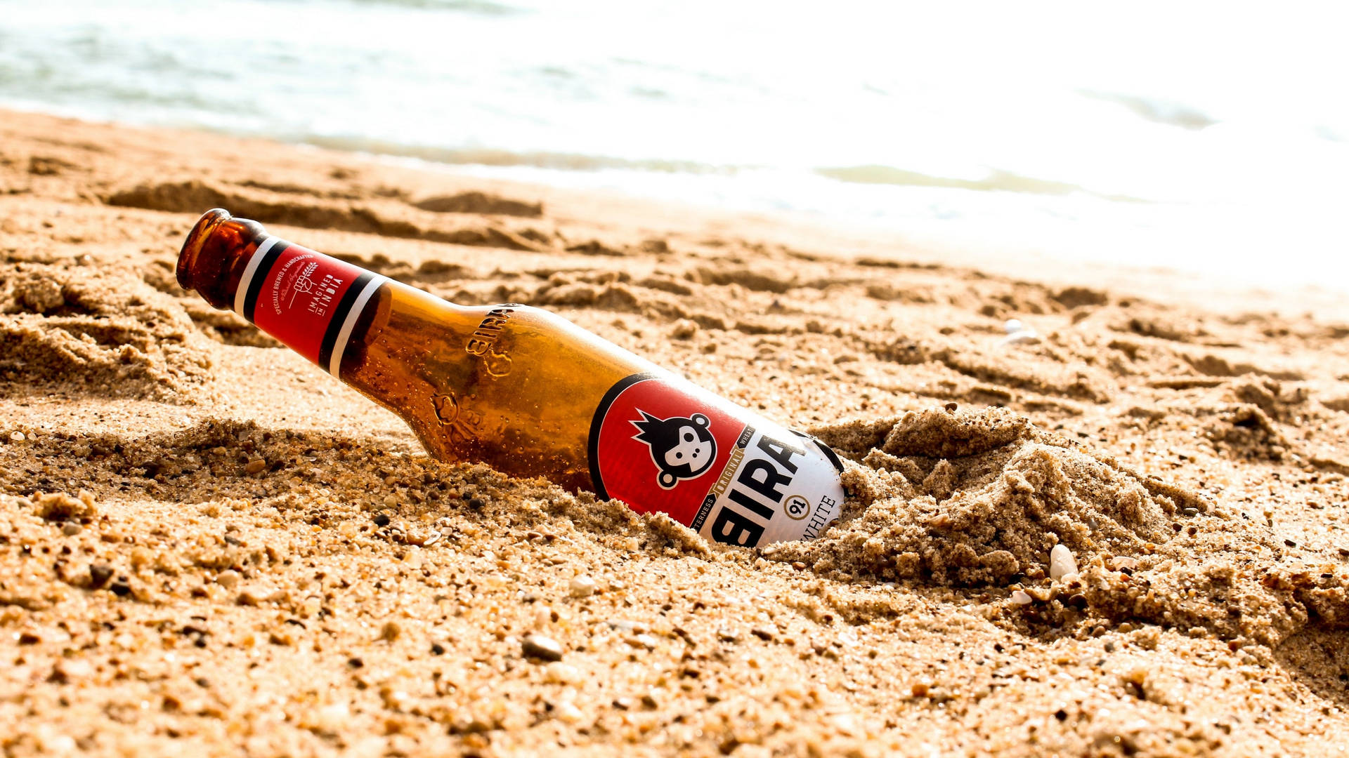 Beer Bottle Buried On The Sand Background