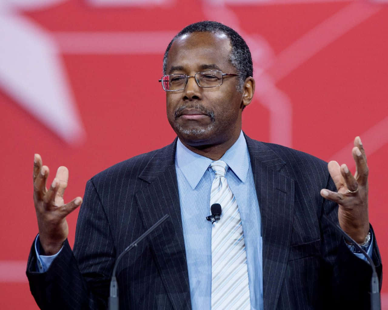 Ben Carson Expressively Speaking At An Event Background