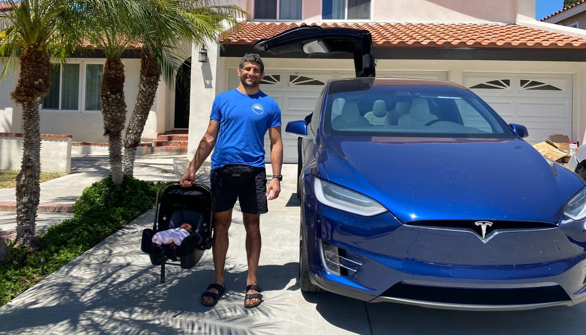 Beneil Dariush Next To Blue Car Background