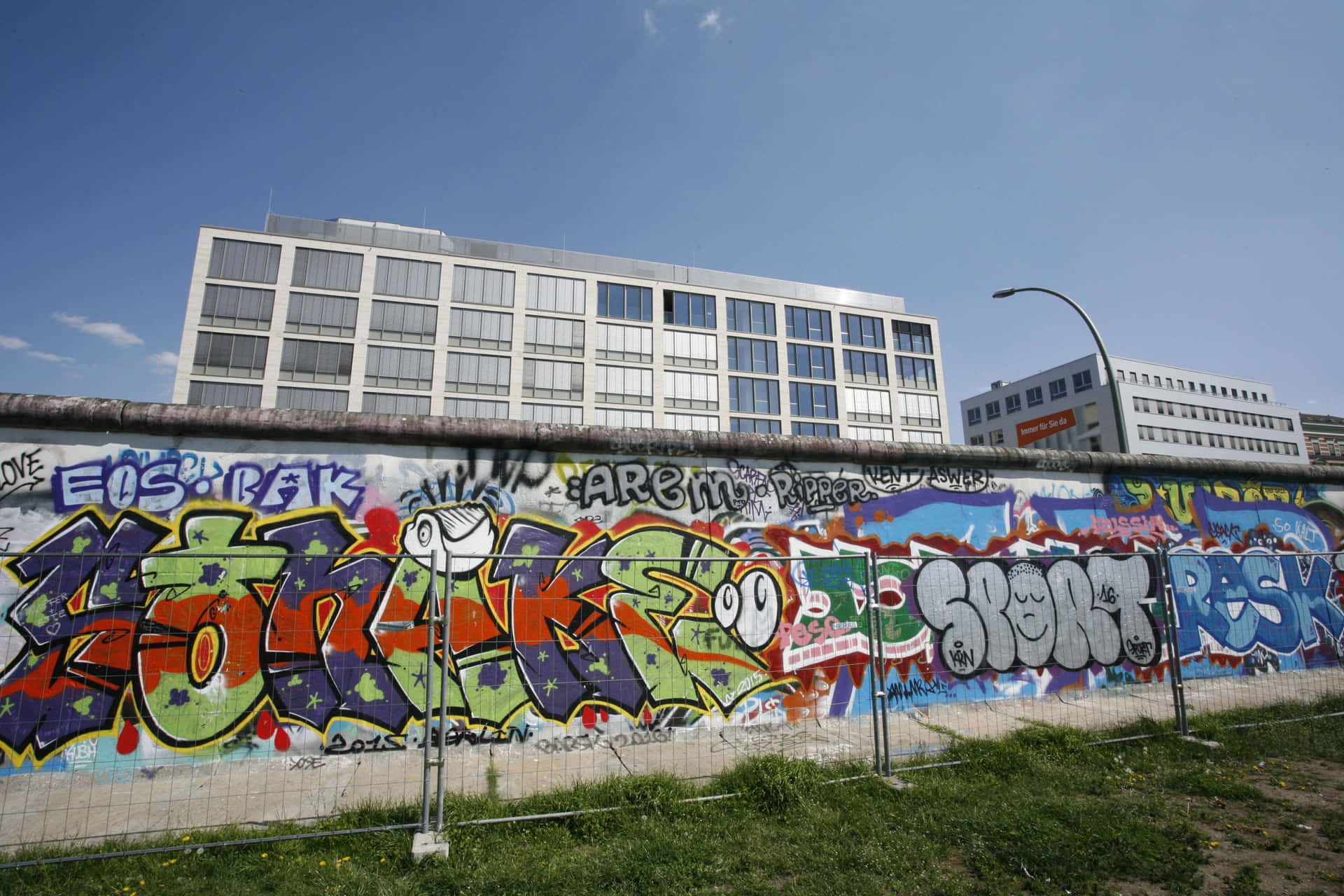 Berlin Wall With Graffiti Against Buildings Background