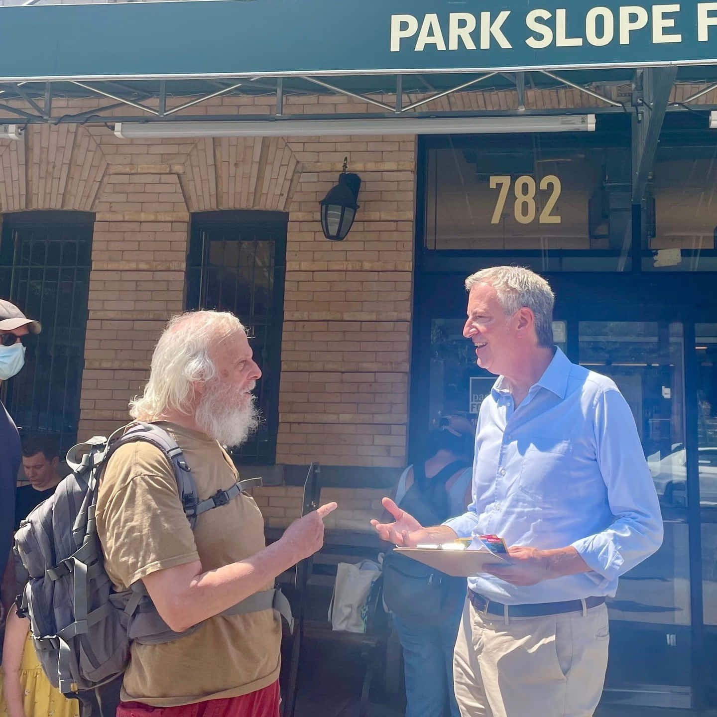 Bill De Blasio Conversing With A Man Background