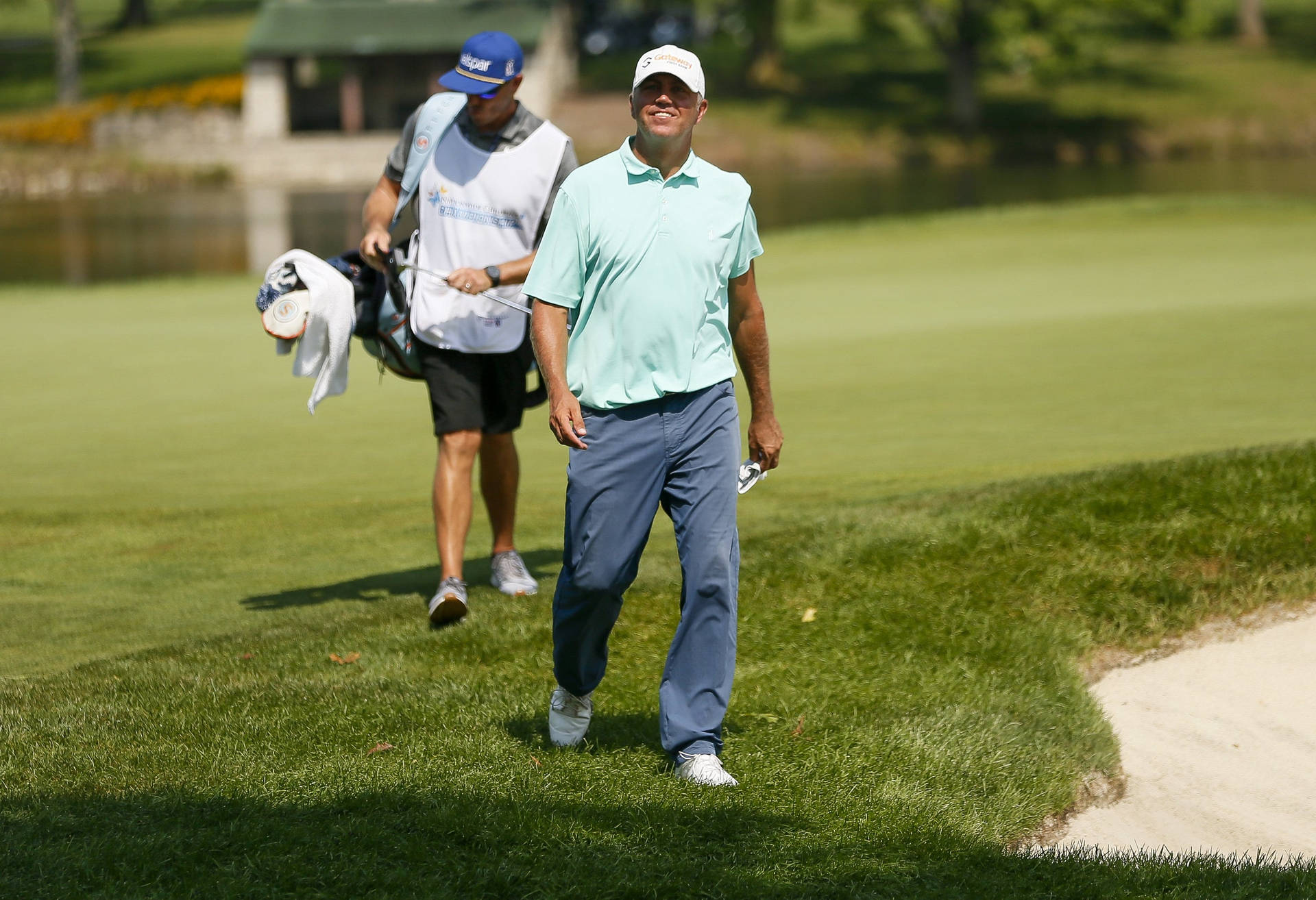 Bill Haas Striding Confidently Across The Golf Course Background