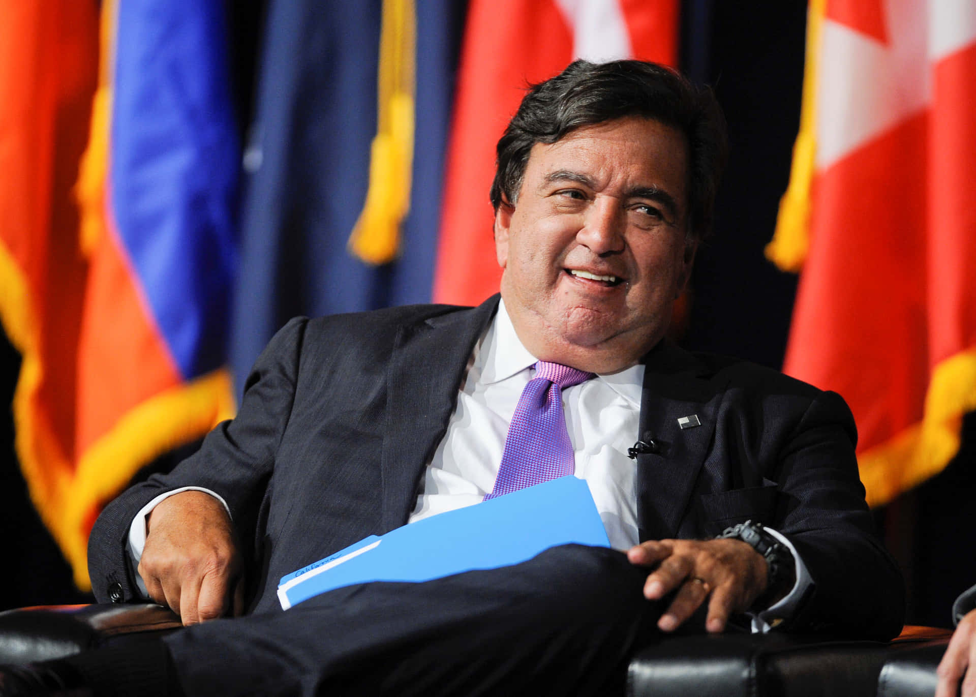 Bill Richardson Smiling And Sitting Down Background