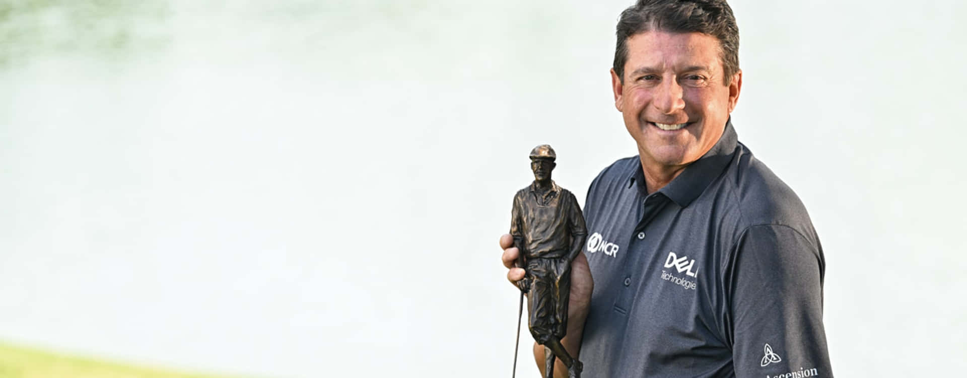 Billy Andrade Holding A Golf Trophy Background