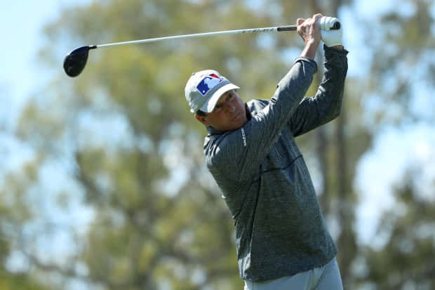 Billy Andrade Swinging A Golf Club Background