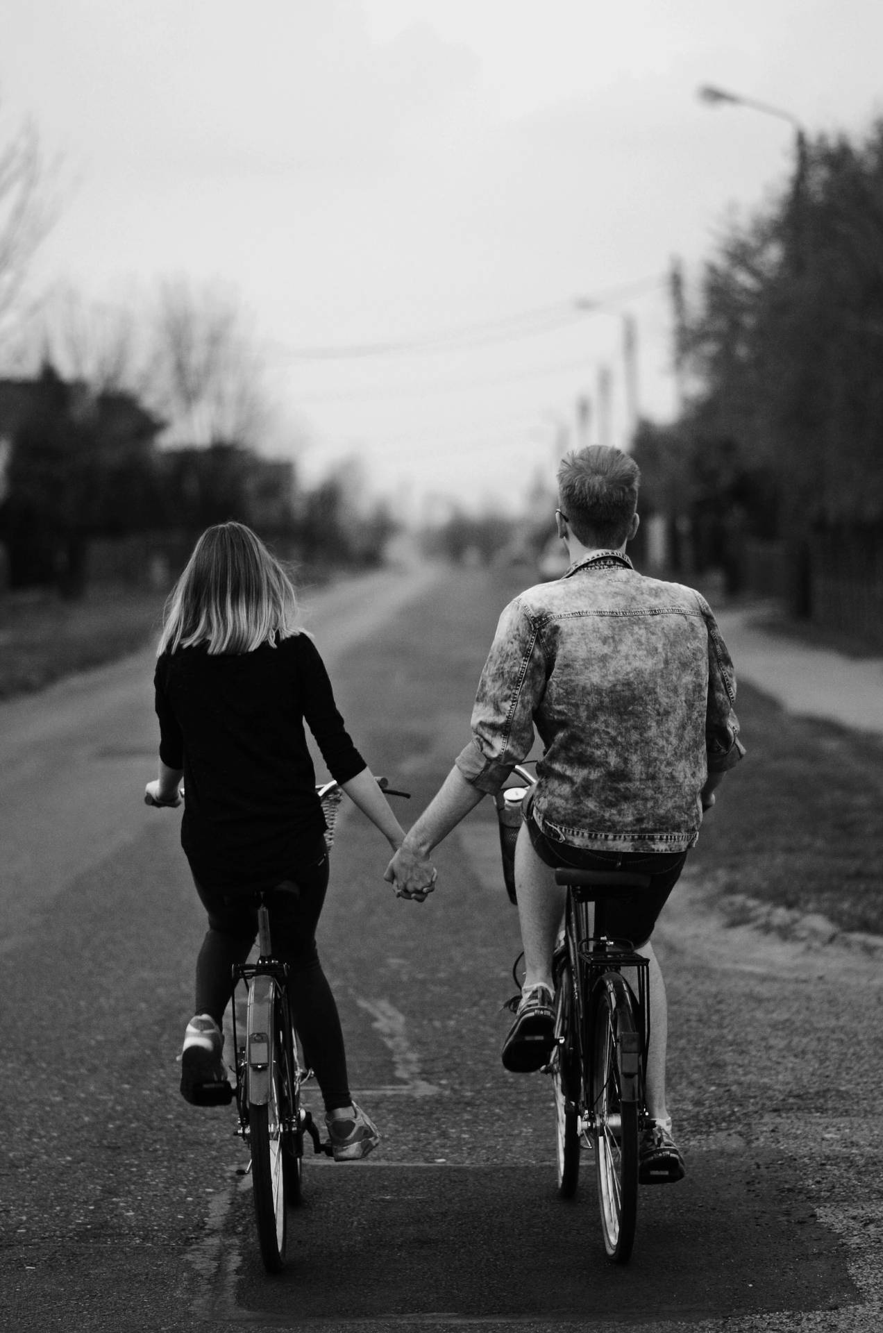 Black And White Holding Hands While Riding Bikes
