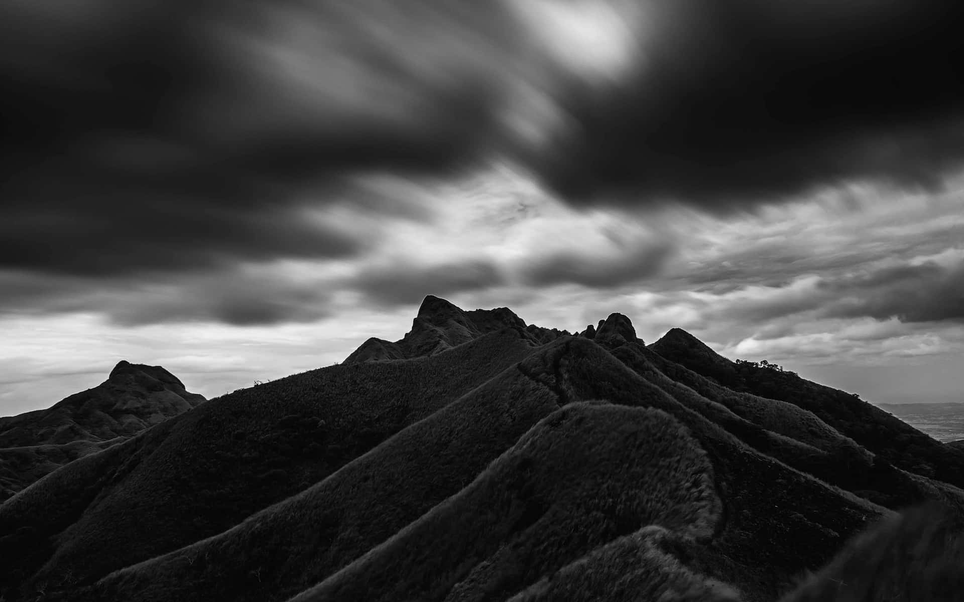 Black Clouds Above Fold Mountains Background