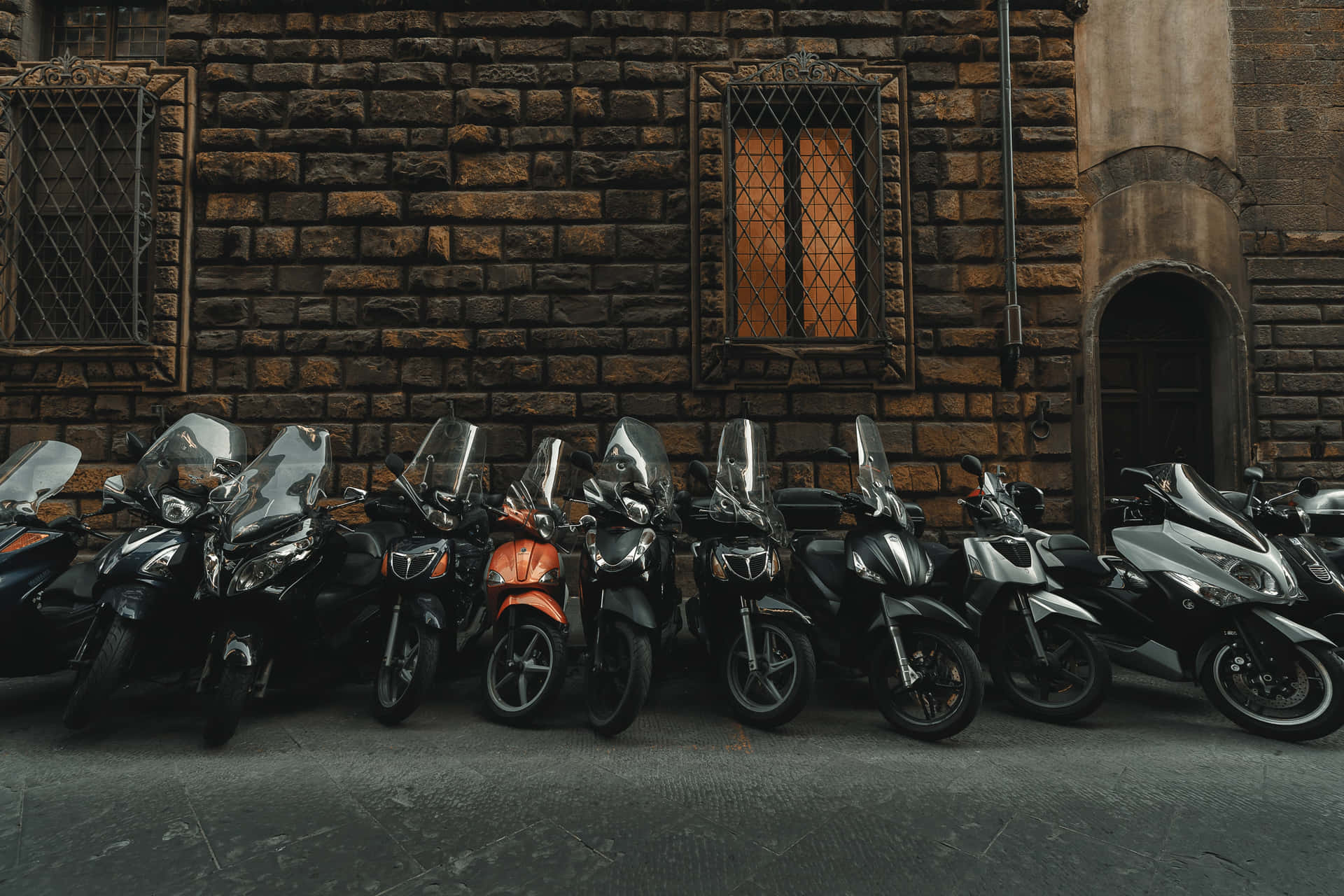 Black Motorcycles Lining Up With A Conspicuous Orange One Background
