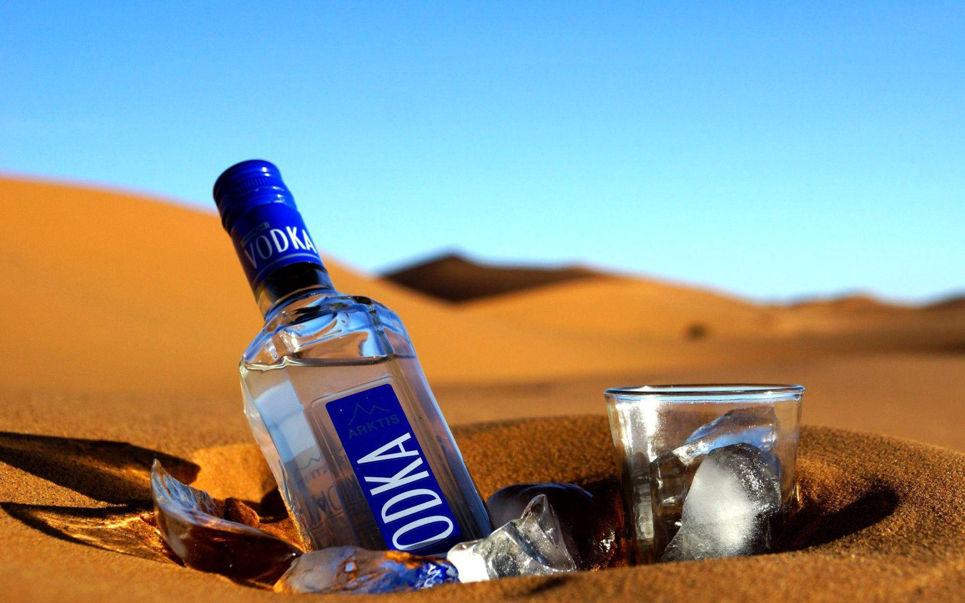 Blue Vodka Bottle And Glass On Desert Sand