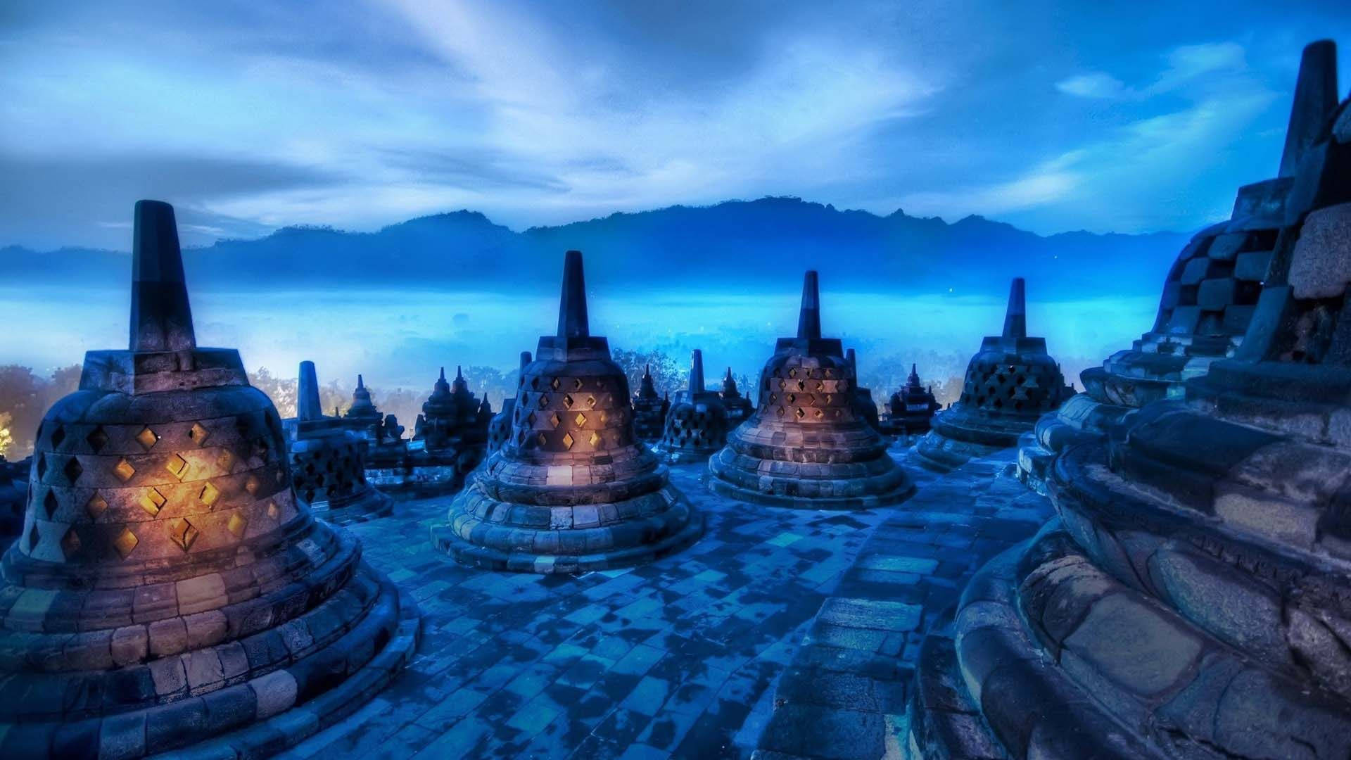 Borobudur Temple At Night With Fog And Mountains Background