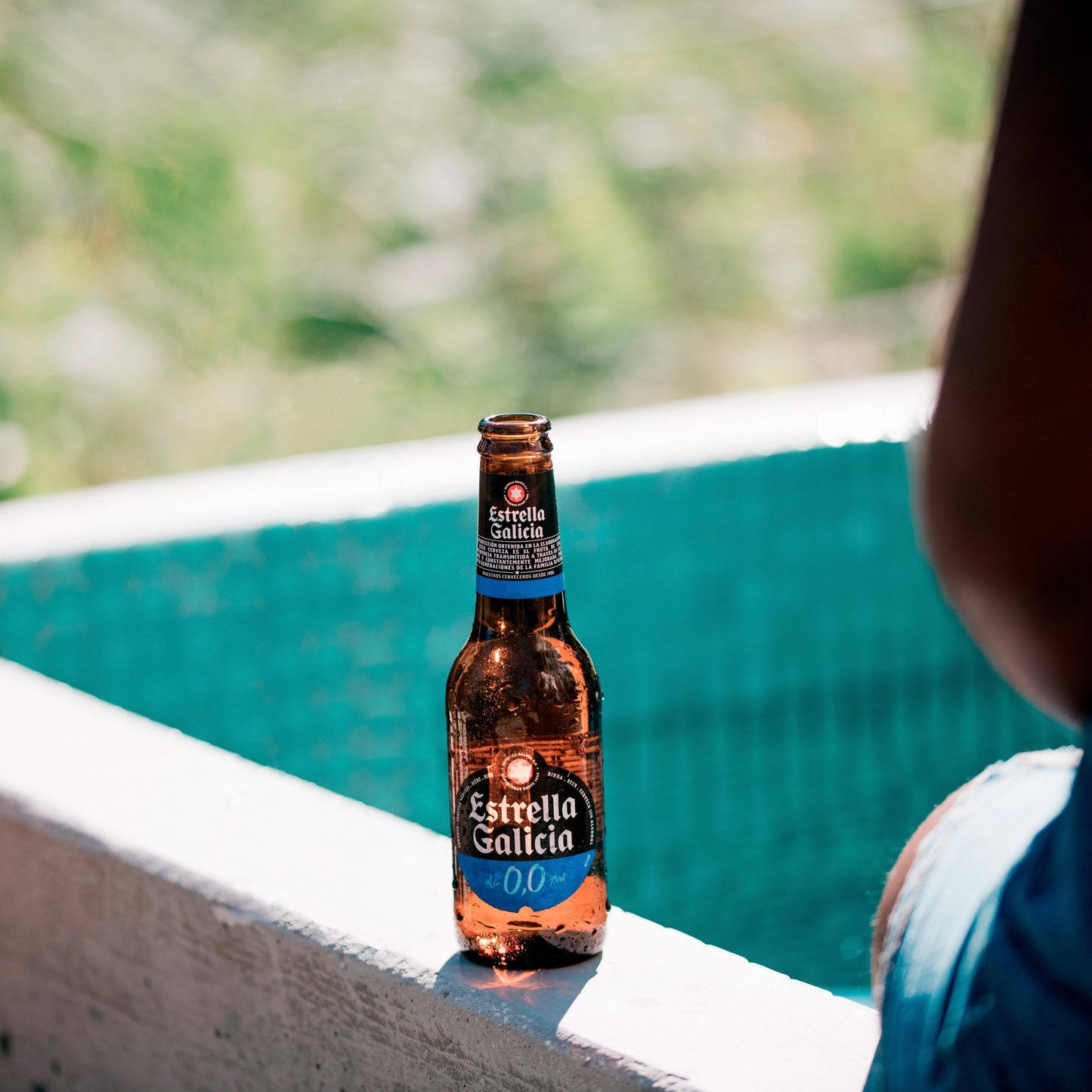 Bottle Of Estrella Galicia By The Pool Background