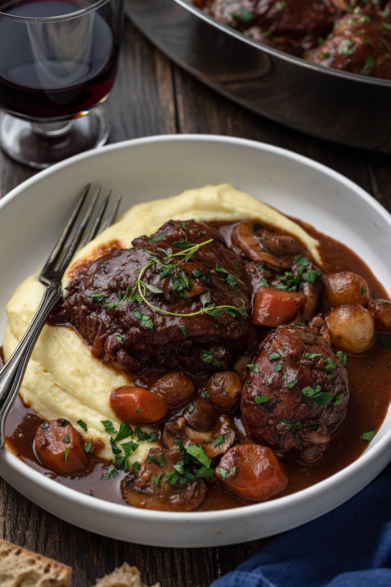 Bowl Of Creamy Coq Au Vin Near A Glass Of Wine