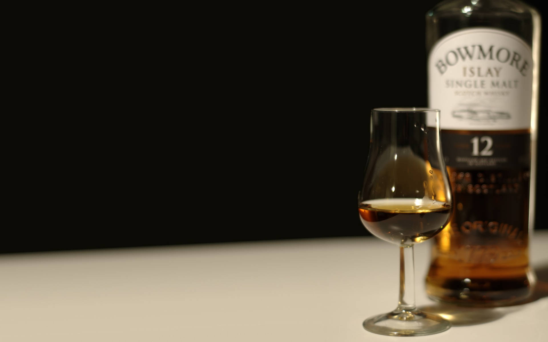 Bowmore 12 Years Old Whiskey With A Tasteful Serving Glass Background