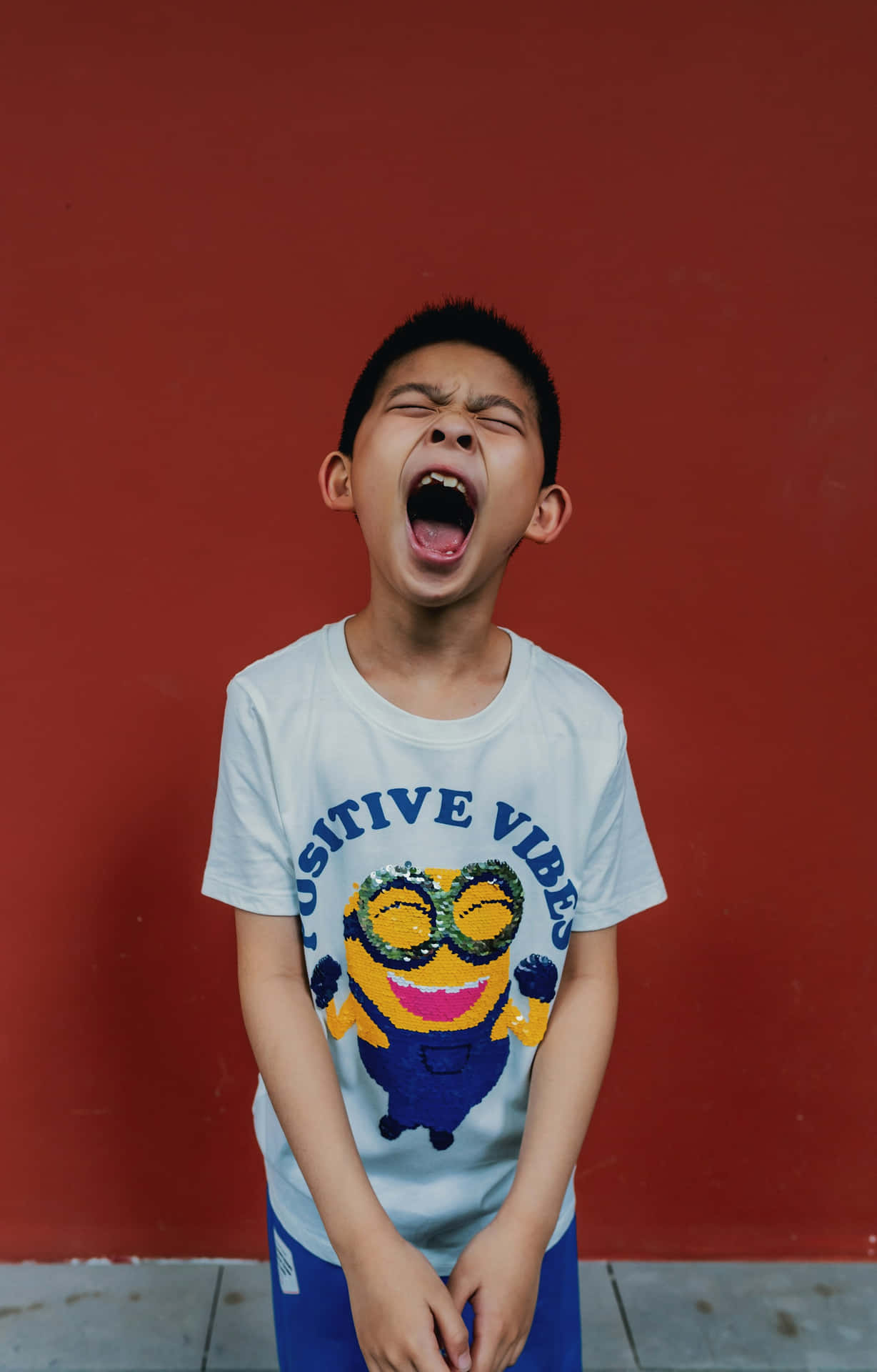 Boy Yawning Against Red Wall Background