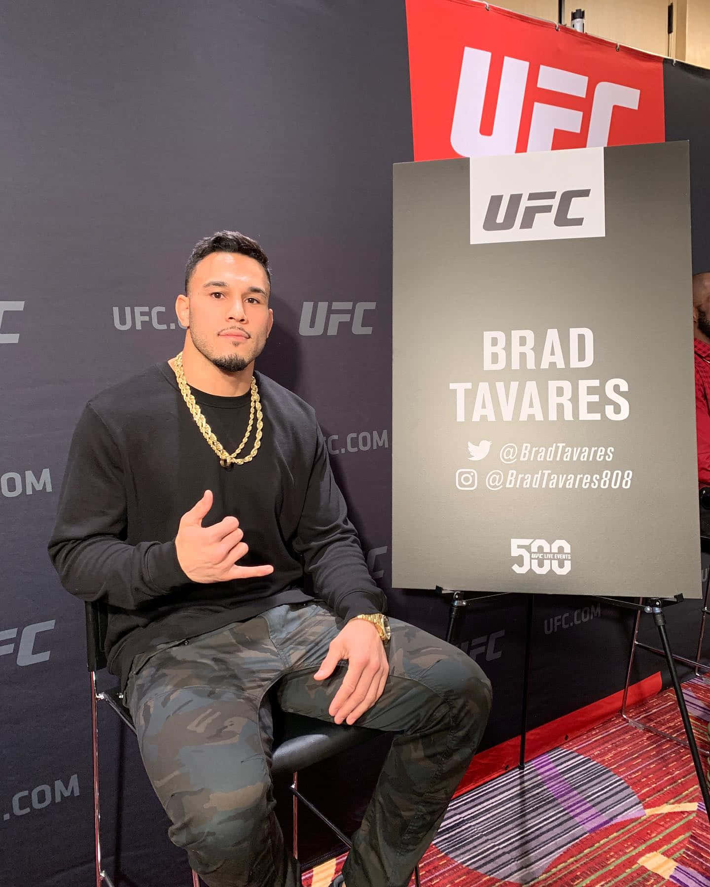 Brad Tavares Posing Next To A Sign Background