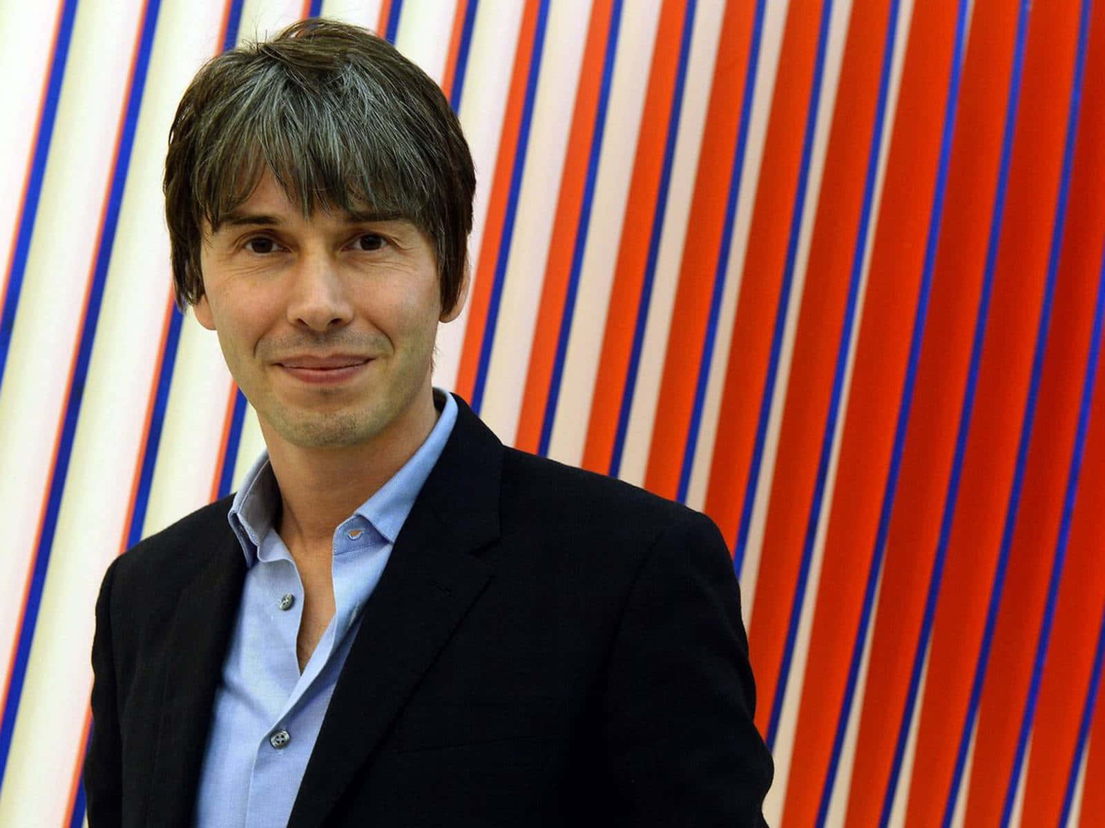Brian Cox Smiling Against Striped Background Background