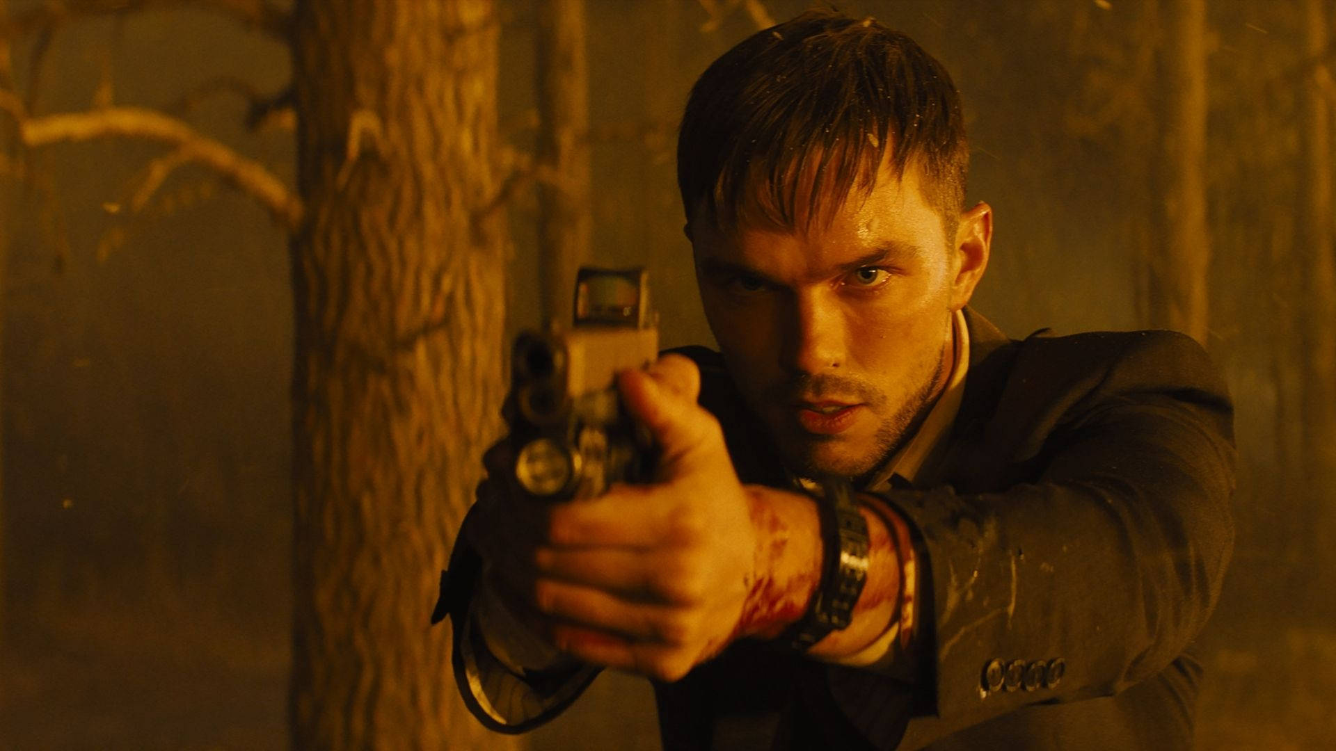 British Actor Nicholas Hoult Holding A Gun Background