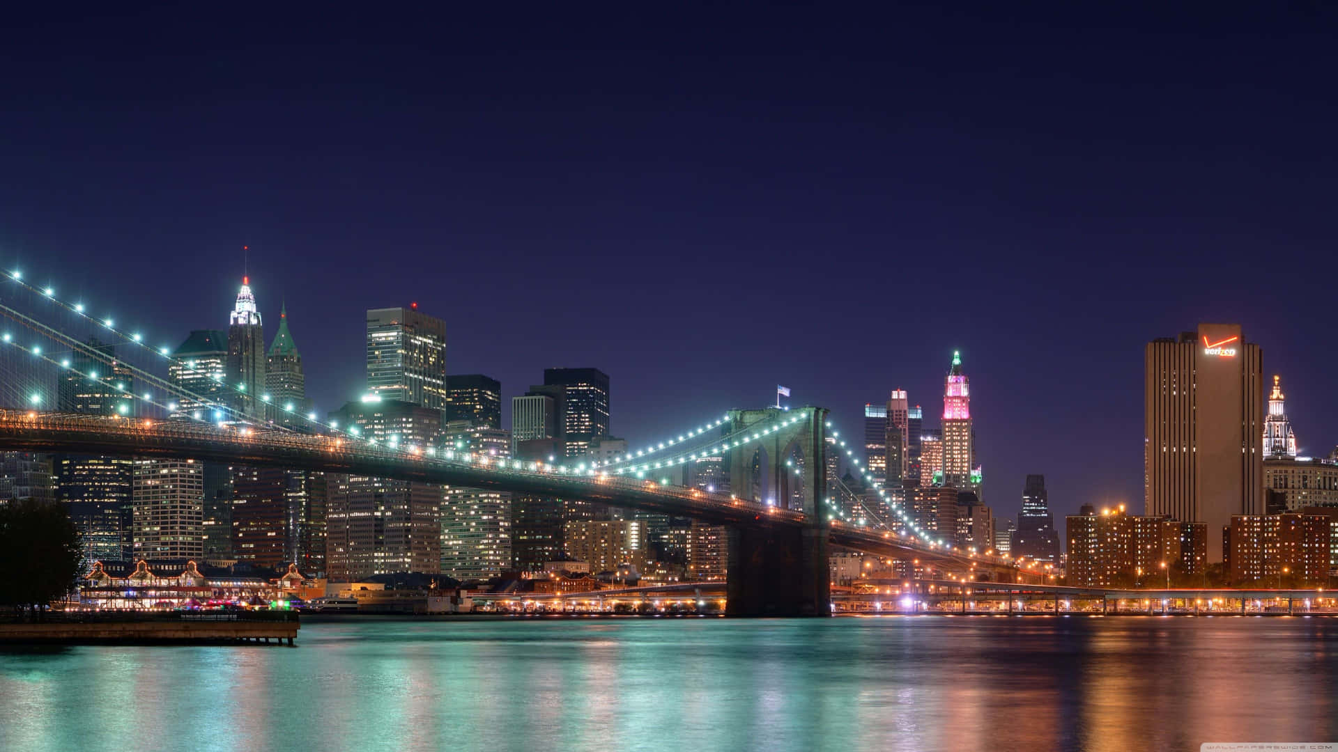 Brooklyn Bridge At Night With The City Lights Background